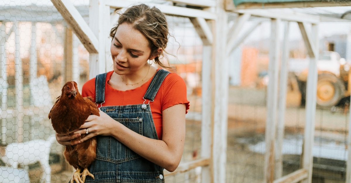 Happy young woman with a brown hen
