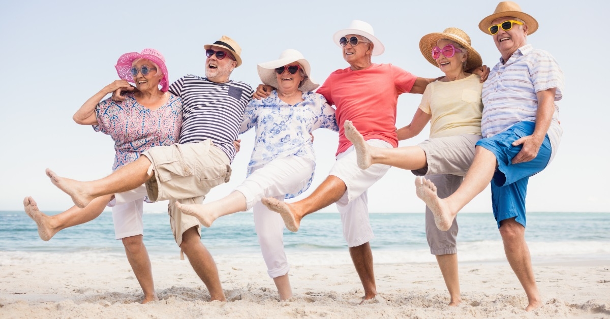 happy senior friends dancing at beach