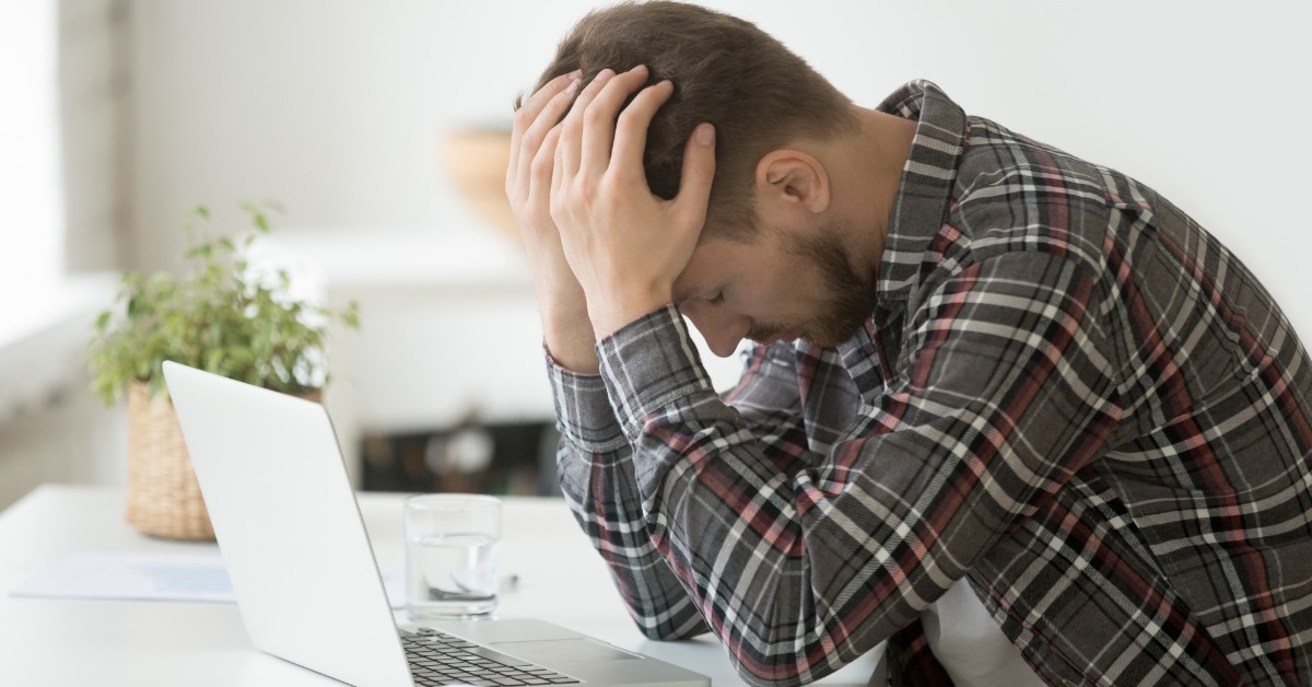 stressed man with laptop at work