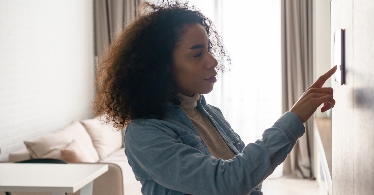 woman adjusting temperature using smart thermostat