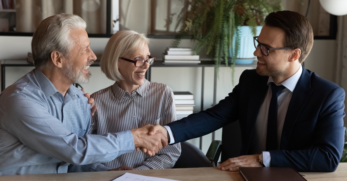 senior couple shaking hands with broker