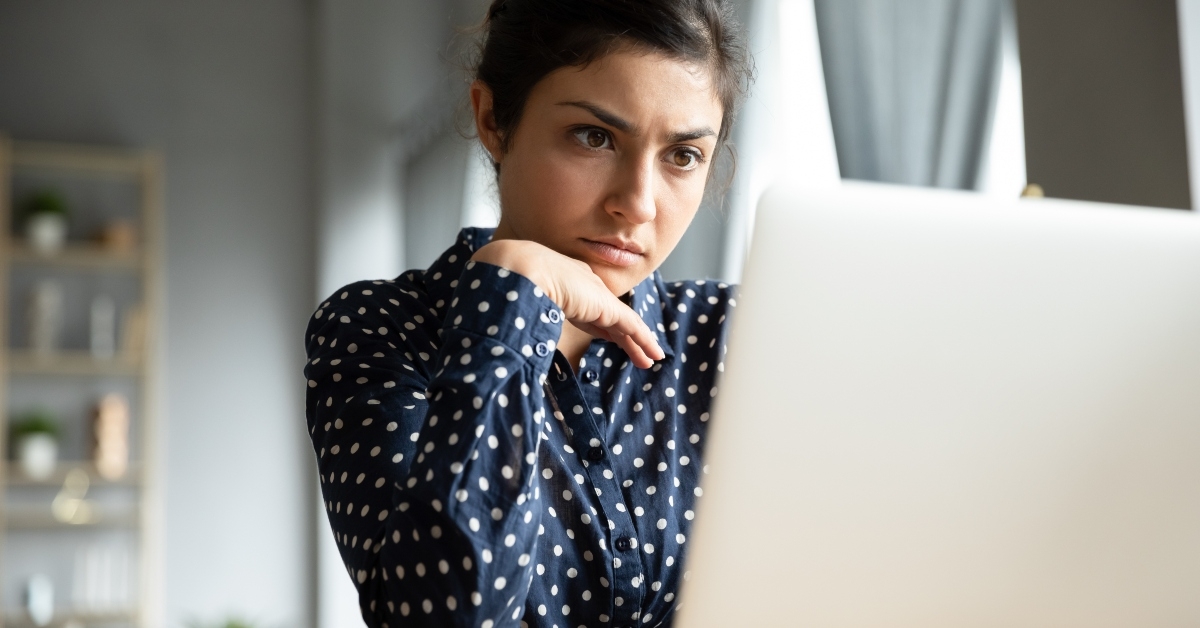 serious indian woman looking at laptop