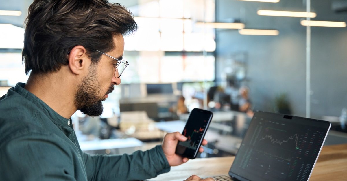 male broker using smartphone and laptop