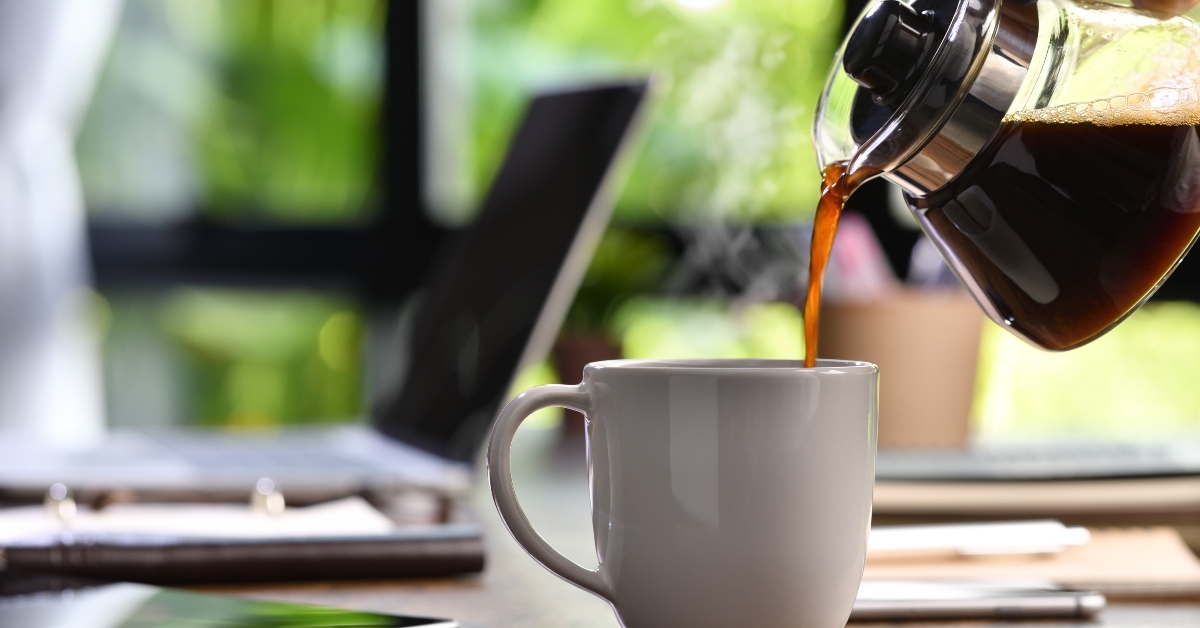 hand pouring steaming coffee