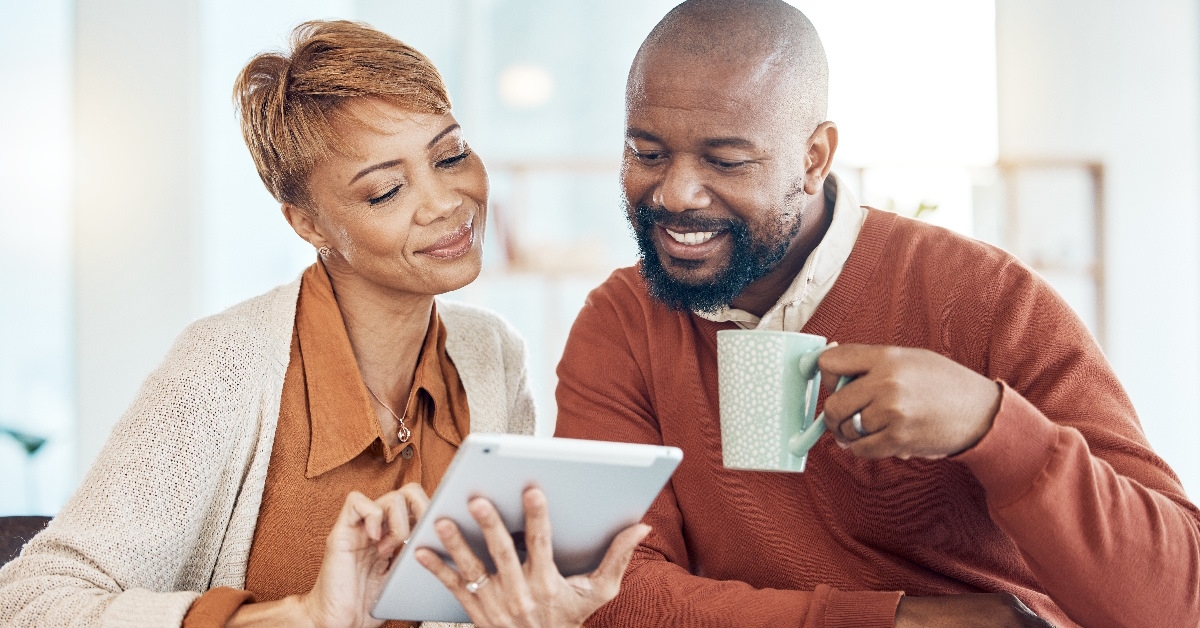 Couple is gazing at a tablet with smiles on their faces.
