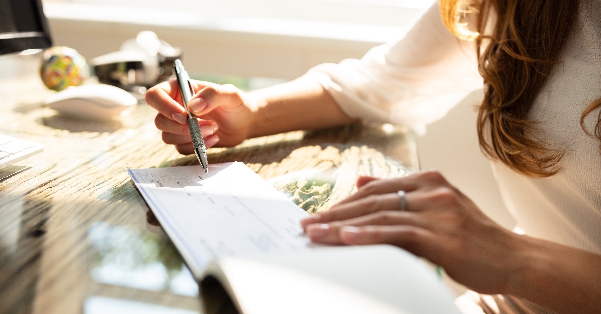 A businesswoman is putting her signature on a check.