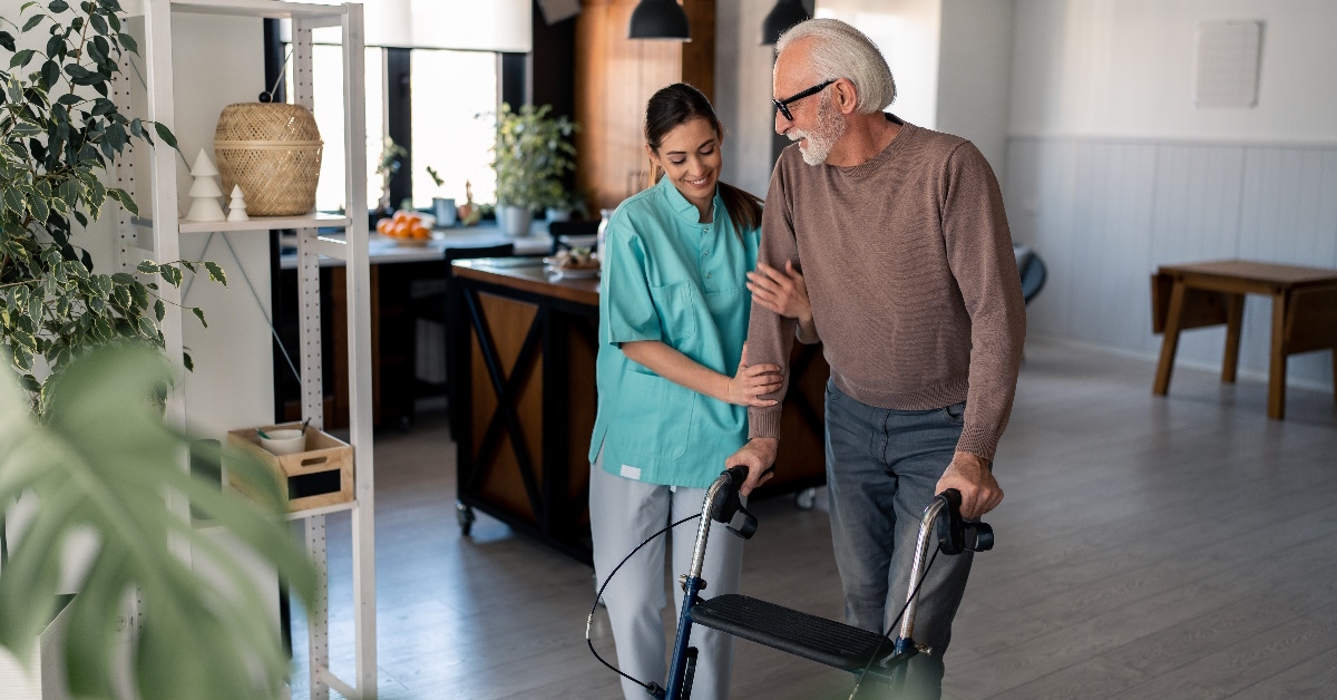 Physiotherapist helping old man to use mobility walker.
