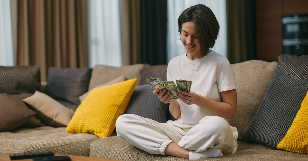 A young woman is tallying her salary in cash.