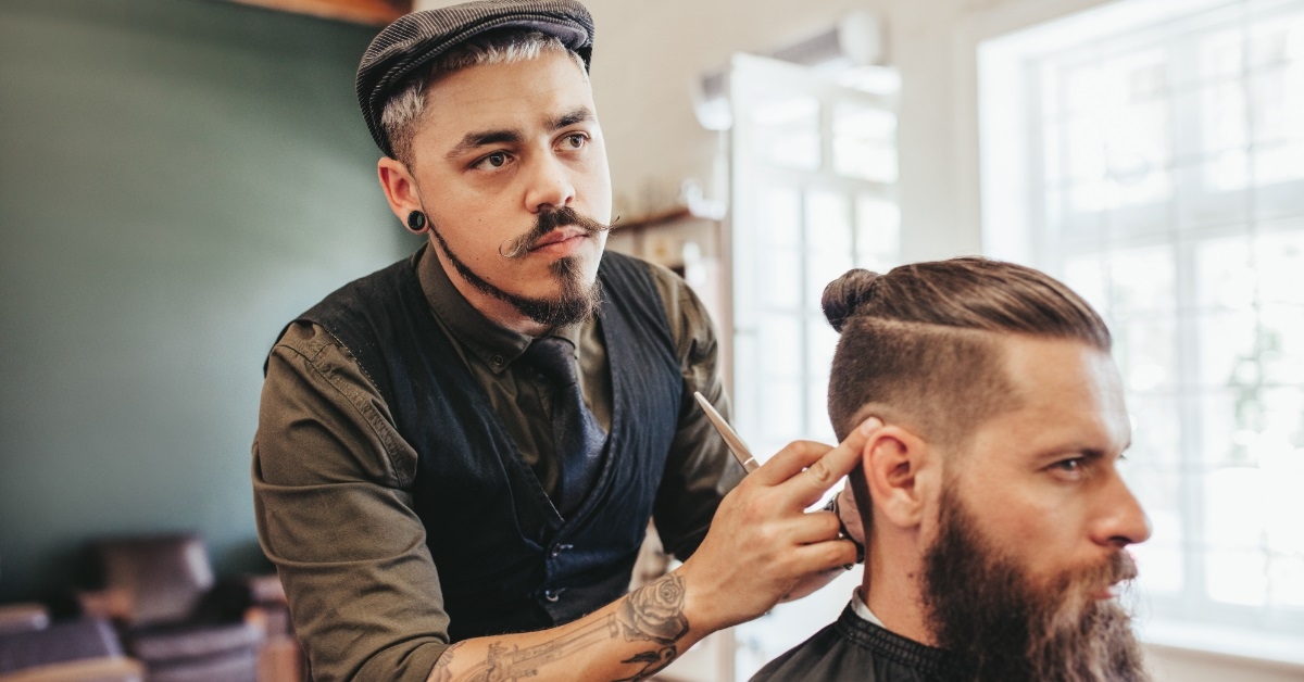 stylish barber giving haircut to man
