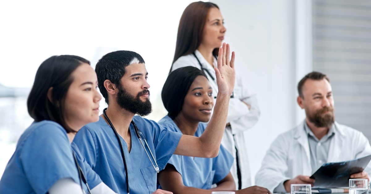 male doctor raising hand in meeting