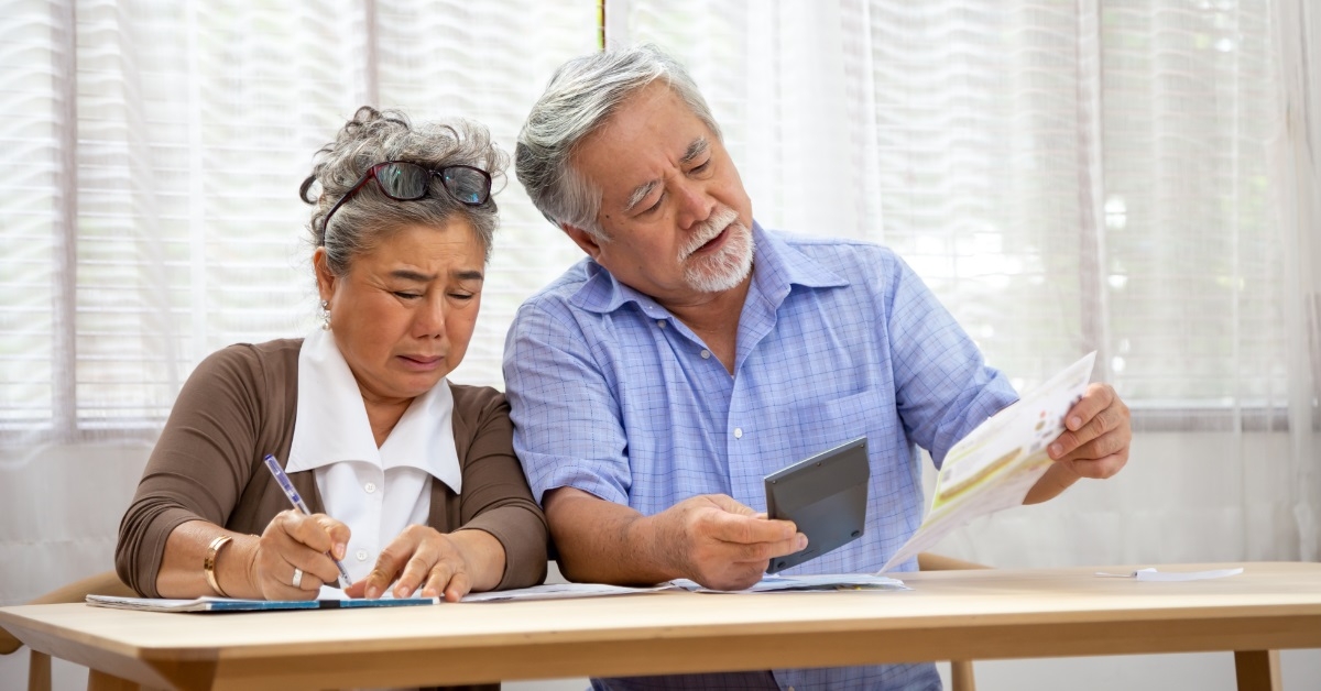 worried senior asian couple reviewing bills