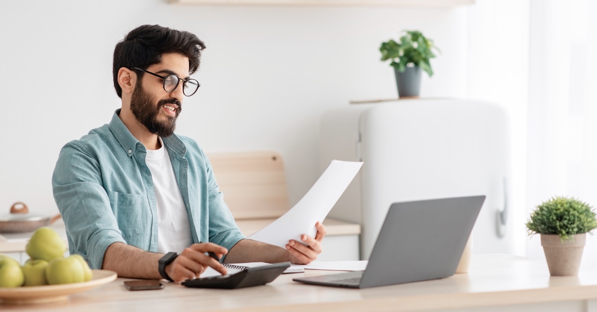 young man calculating taxes using calculator