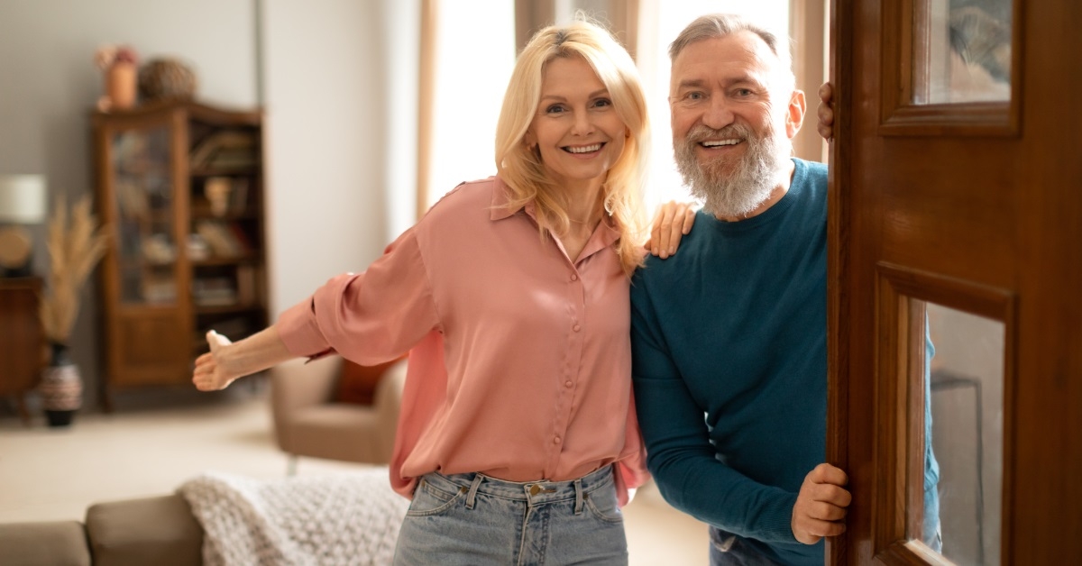 senior couple welcoming guests at gate
