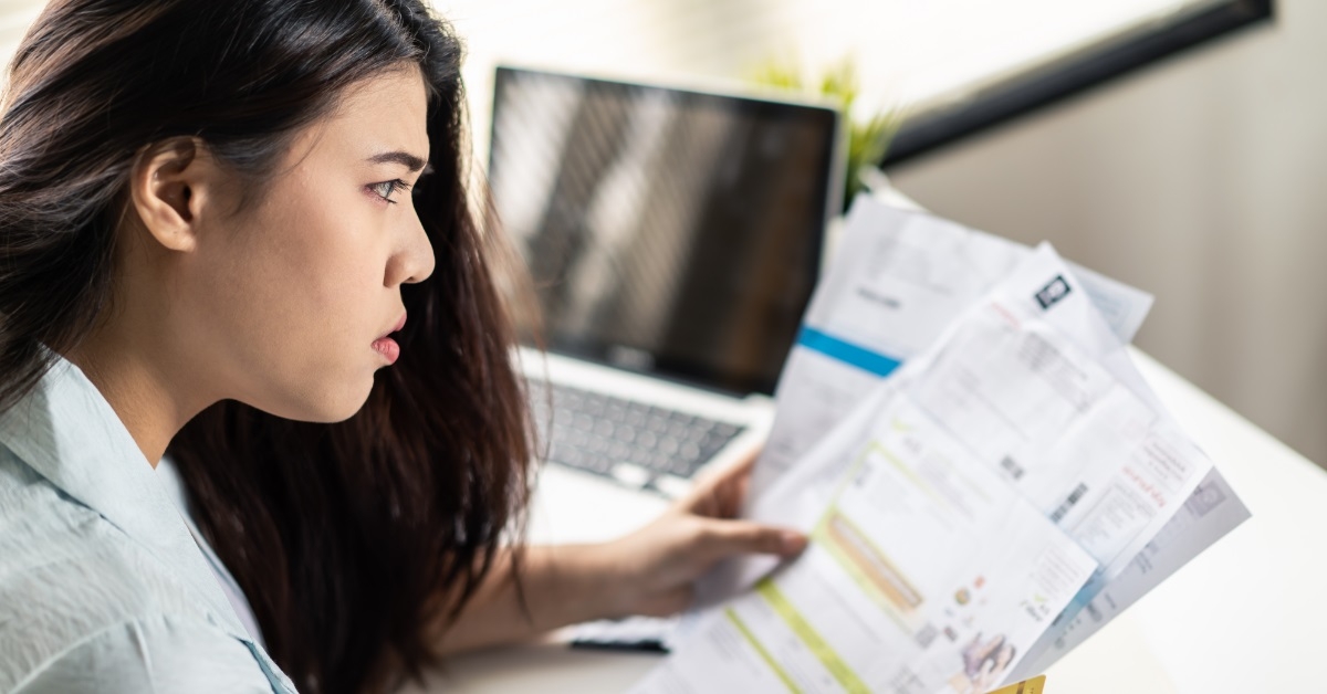 stressed asian woman reviewing utility bills