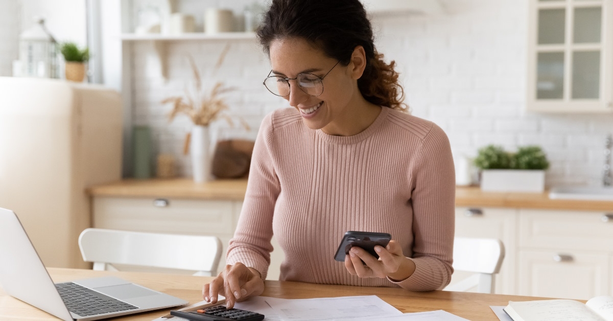happy woman calculating bills at home