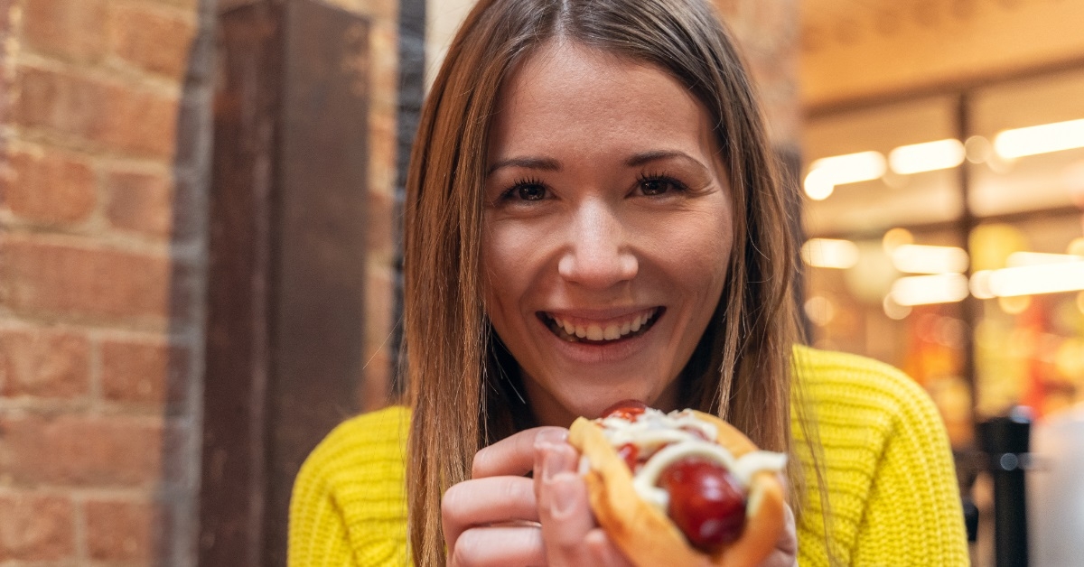 happy woman eating hot dog