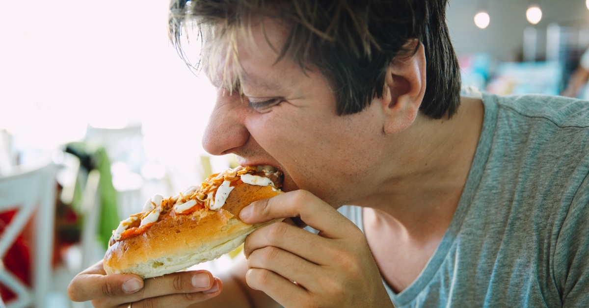 man having hot dog in cafe
