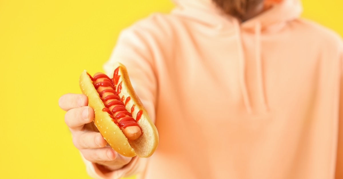 man in hoodie holding hot dog