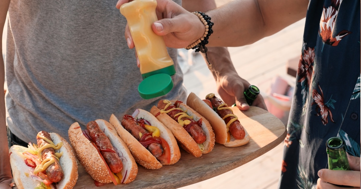 men adding sauce on hot dogs