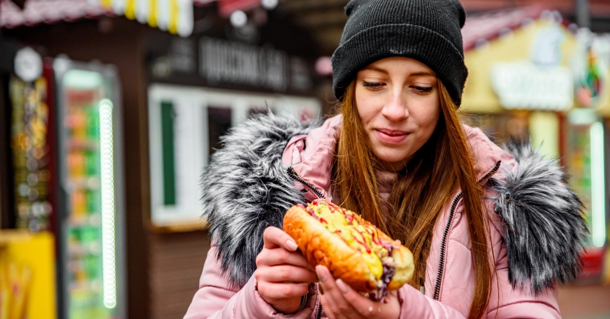 woman enjoying hot dog during winter