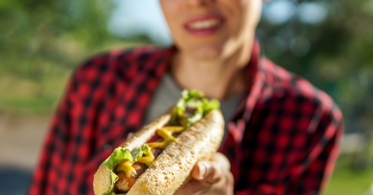 woman holding hot dog outdoors