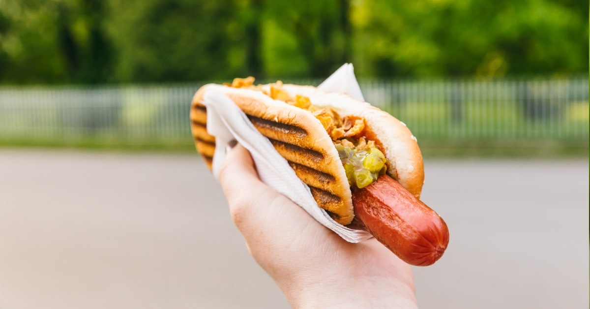woman holding pickled hot dog outdoor
