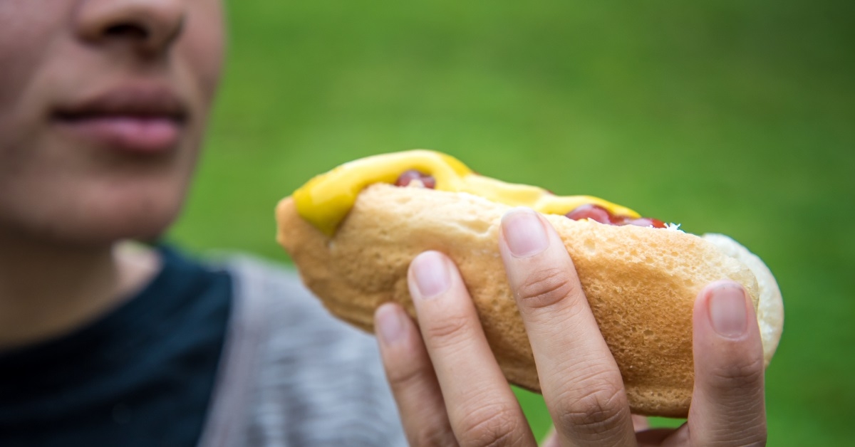woman holding saucy hot dog