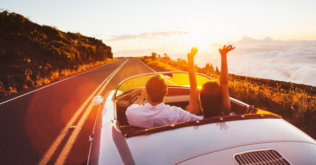 couple driving corvette at sunset