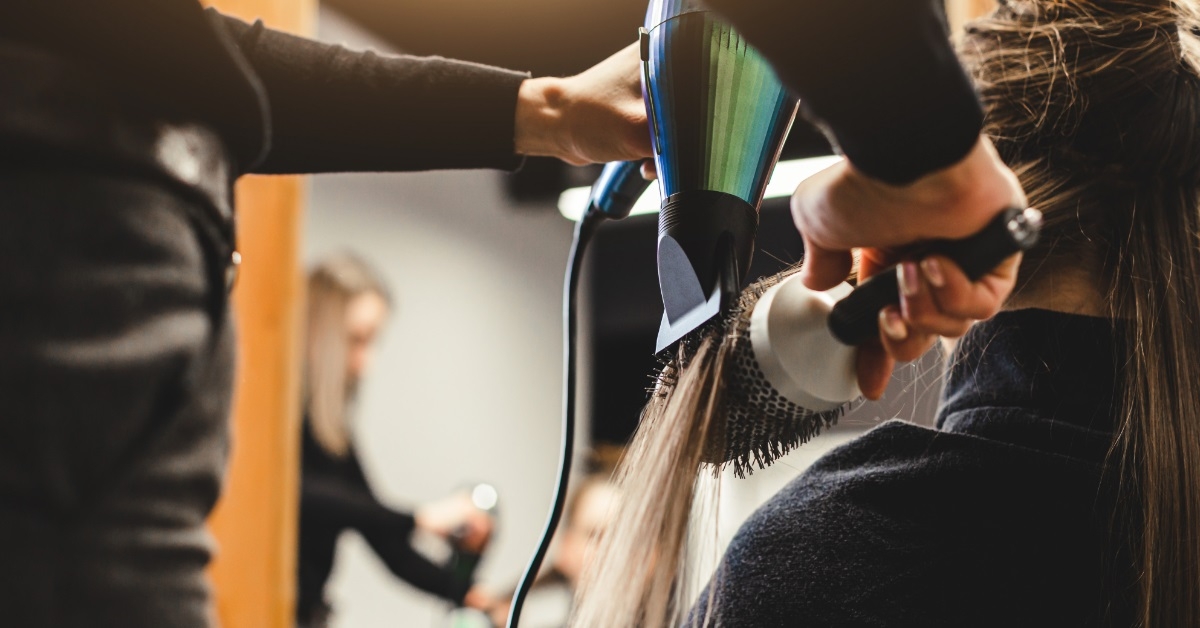 female hairdresser using hairdryer on client