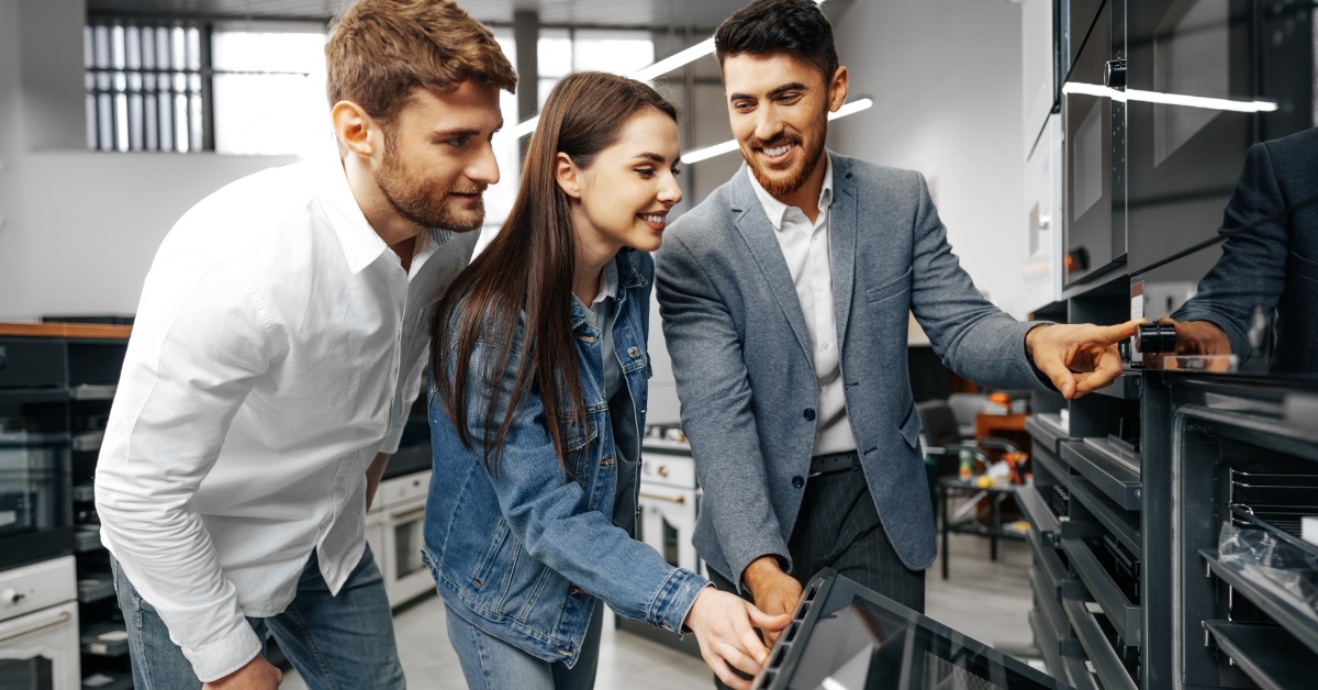 male assistant showing appliances to couple