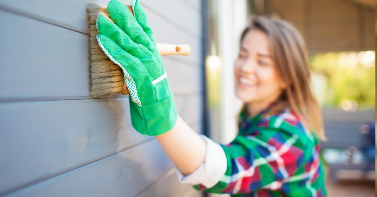 woman applying protective varnish on wall