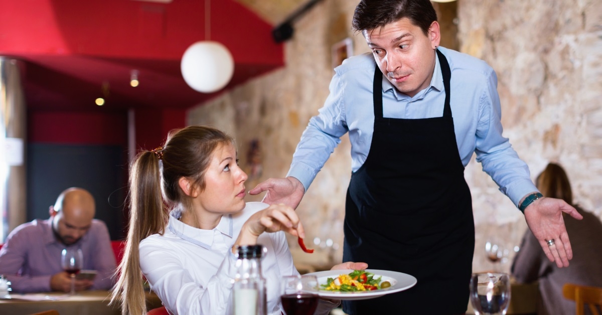 male waiter apologizing to female customer