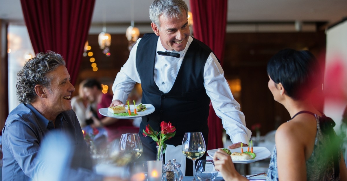 waiter serving fancy dishes to couple
