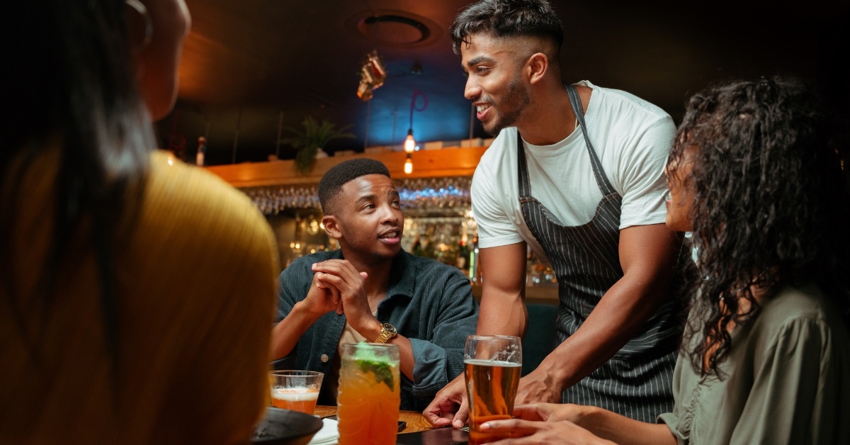 male waiter serving multi ethnic friends