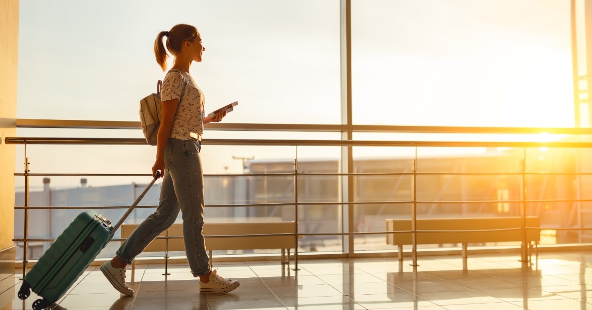 woman at airport window with suitcase 