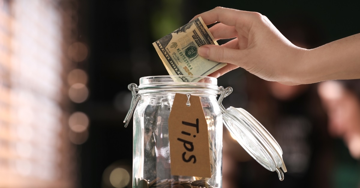 woman putting banknotes into glass jar