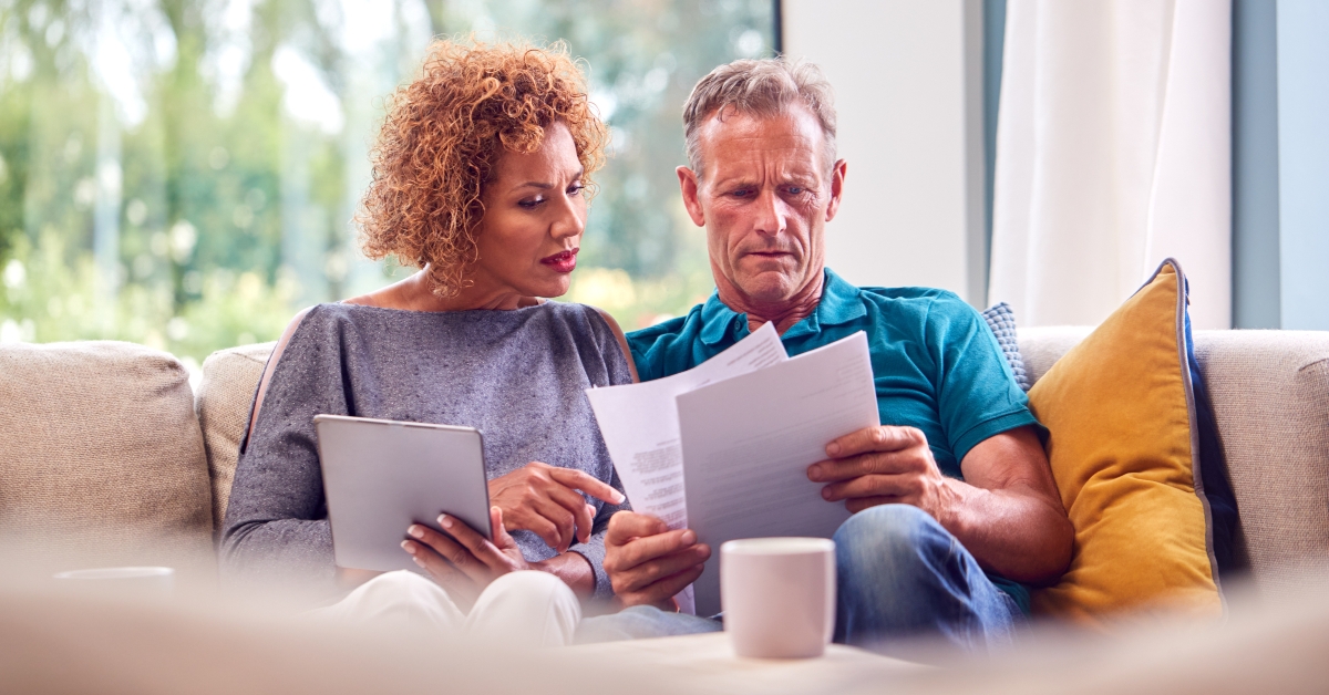 worried senior couple sitting on sofa