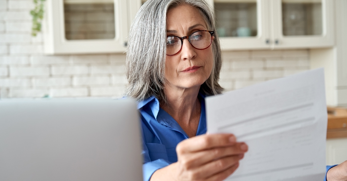 mature woman reading paper bill