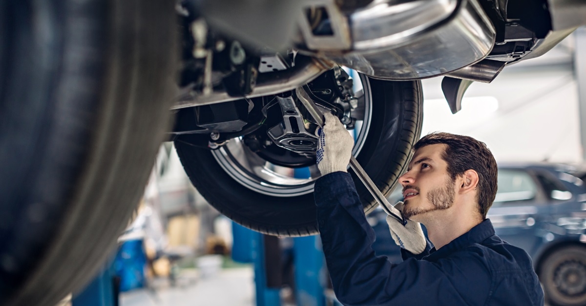 mechanic examining car suspensions at workshop