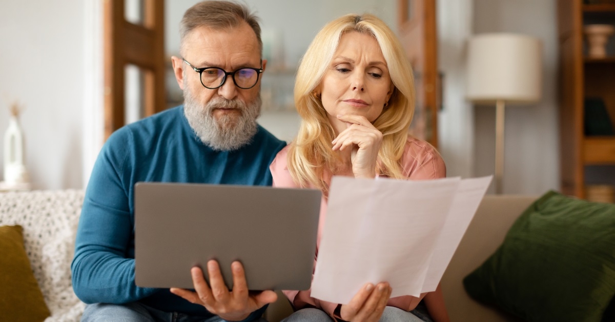 senior couple reviewing bills using laptop