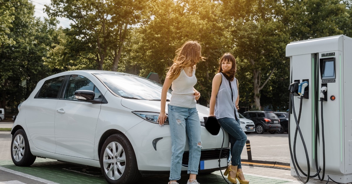 women at electric car charging station