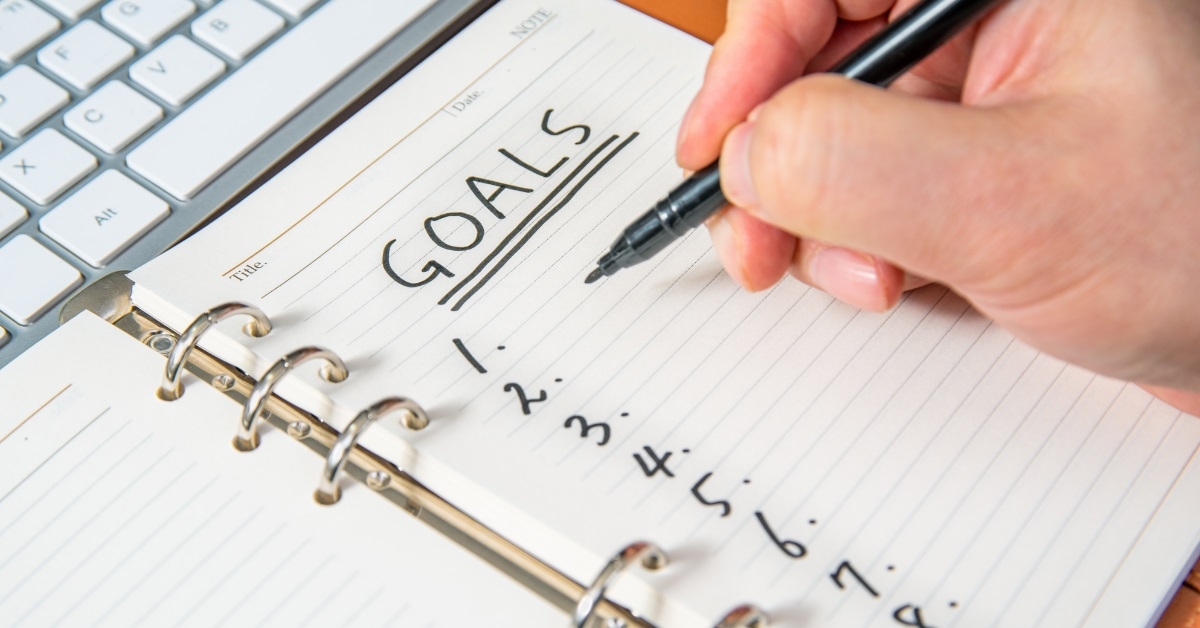 man enlisting goals on notepad