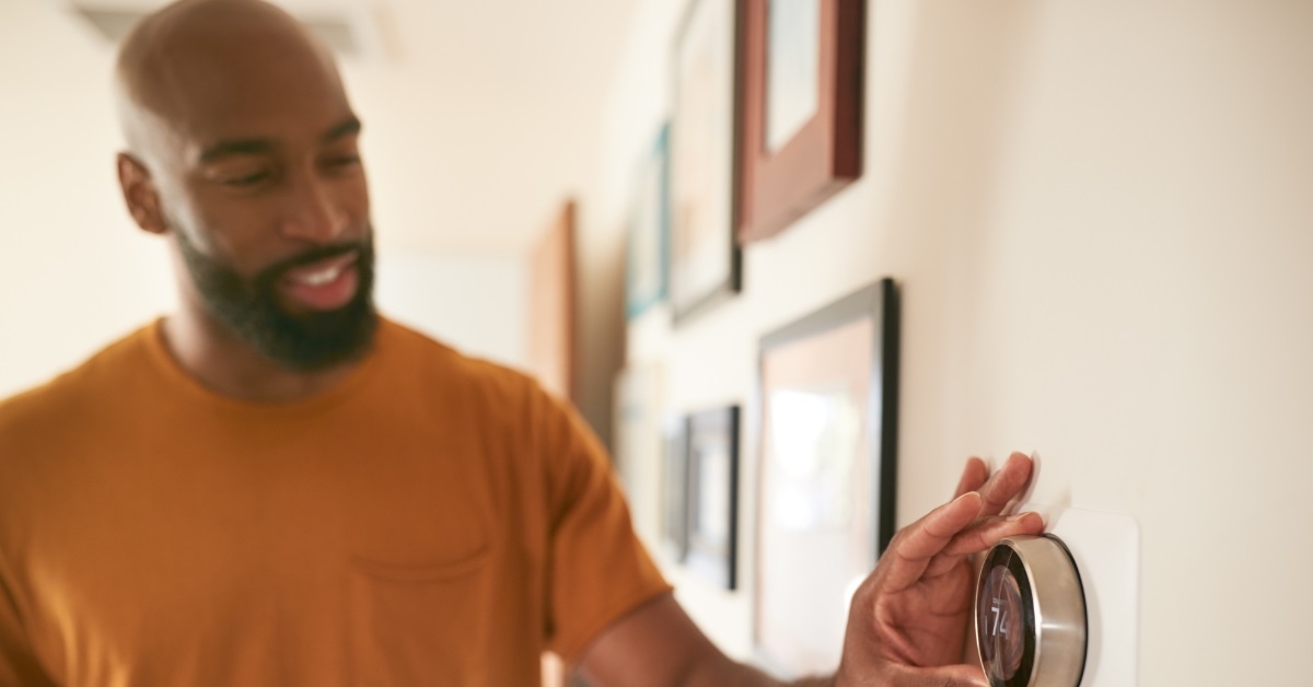 man adjusting thermostat at home