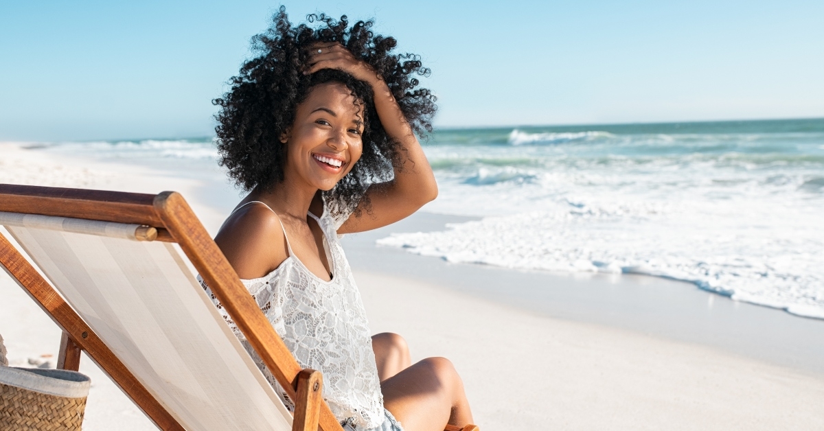 woman sitting on deck chair at beach