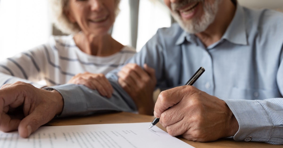 senior couple signing health insurance contract
