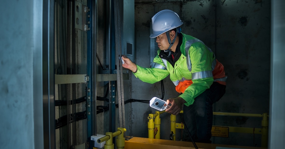skilled male technician fixing elevator shaft