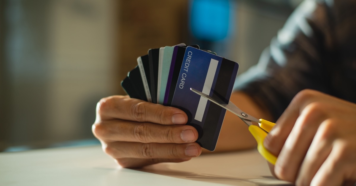 frustrated man cutting cards with scissors