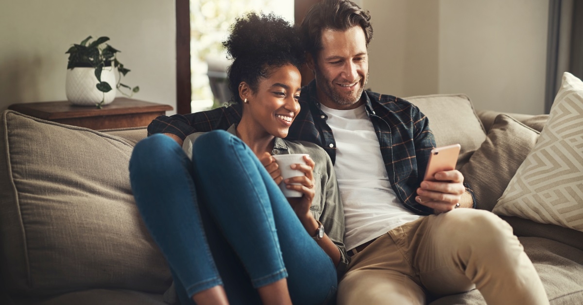happy multi ethnic couple scrolling smartphone