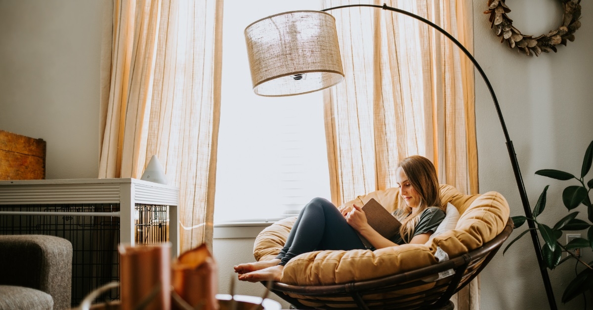 woman reading novel on stylish chair