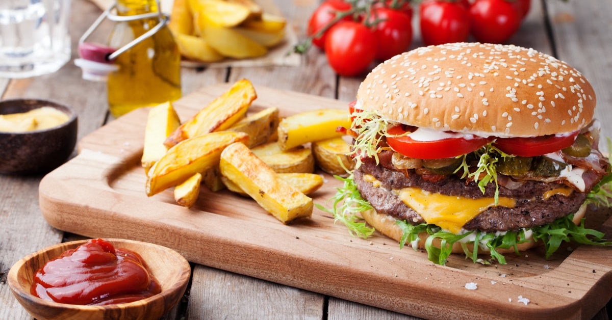 hamburger with fries on cutting board